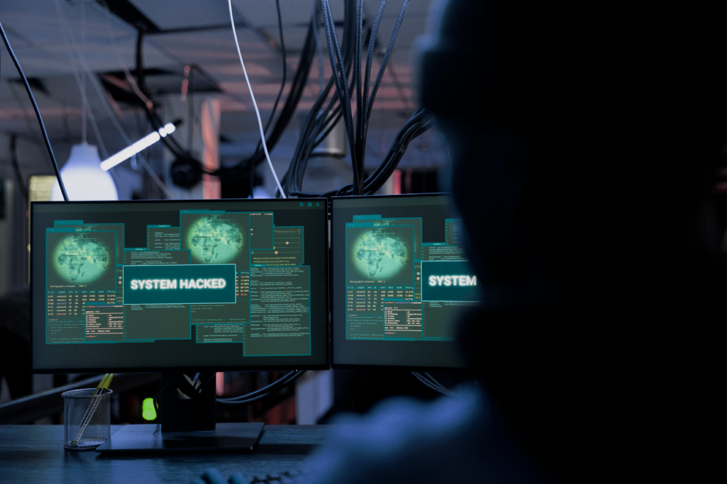 Computer screens with "SYSTEM HACKED" alert message